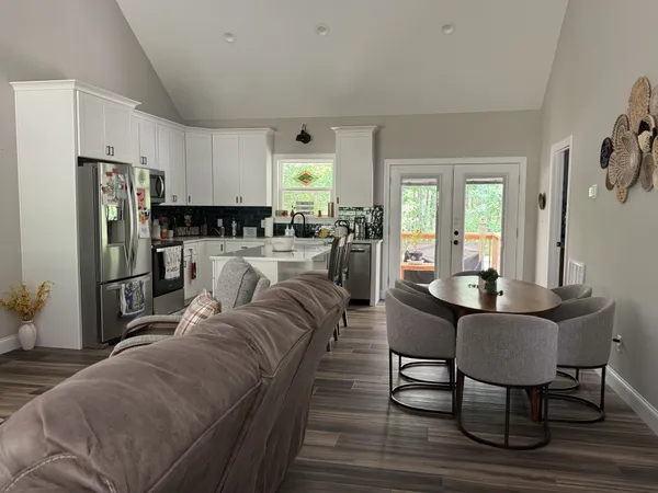 a living room with stainless steel appliances a table chairs and a refrigerator