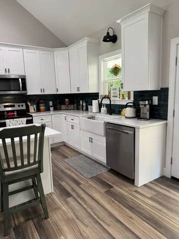 a kitchen with granite countertop a sink a stove cabinets and wooden floor