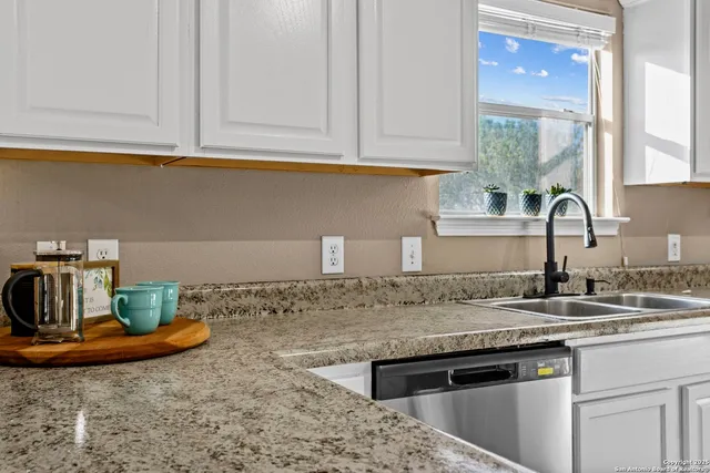a kitchen with kitchen island granite countertop a sink a stove and cabinets