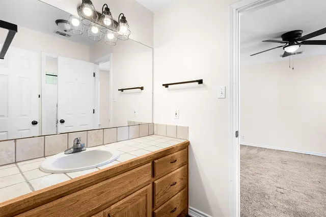 a bathroom with a granite countertop sink a mirror and a shower