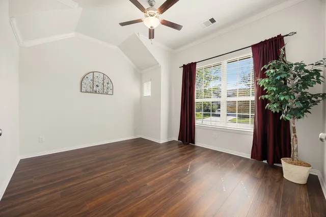 a view of an empty room with a window and wooden floor