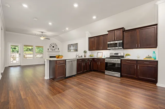 a kitchen with stainless steel appliances wooden floors a refrigerator and a stove top oven