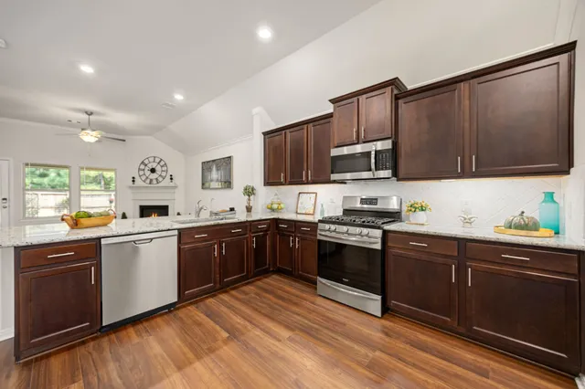 a kitchen with stainless steel appliances granite countertop wooden cabinets a stove top oven a sink and dishwasher