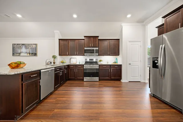 a large kitchen with stainless steel appliances a refrigerator and a stove top oven