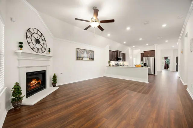 a view of a livingroom with a fireplace a fireplace a ceiling fan and wooden floor