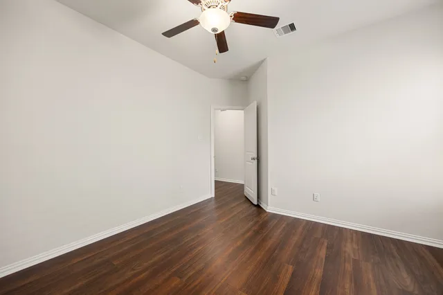 an empty room with wooden floor chandelier fan and closet area