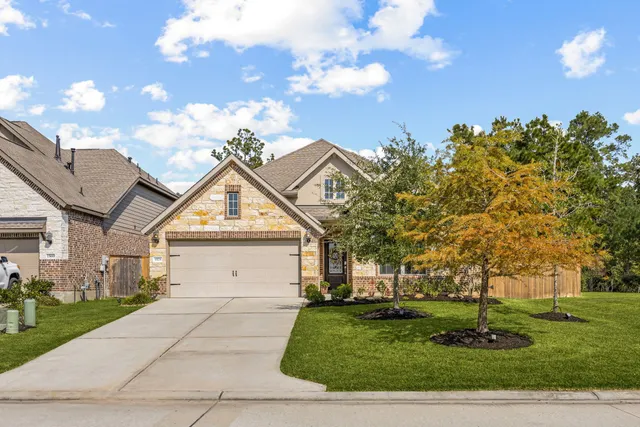 a view of a white house next to a yard with big trees