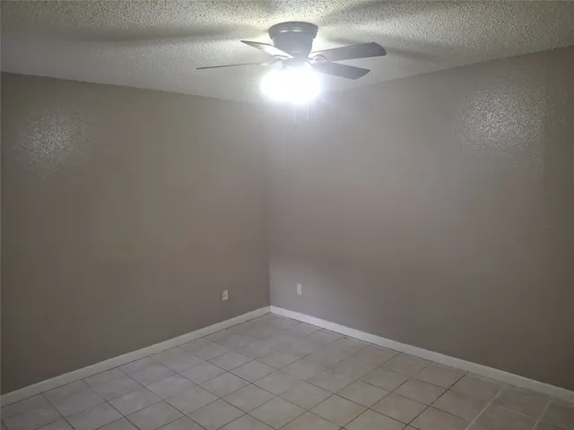 a view of an empty room with window chandelier fan