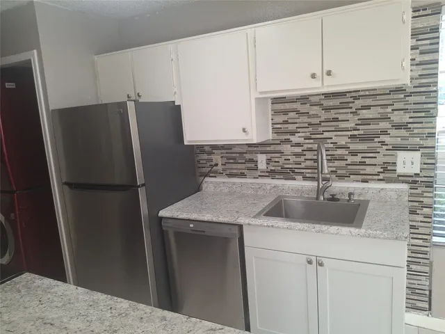 a kitchen with a refrigerator sink and cabinets