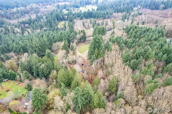 an aerial view of residential house with outdoor space and trees all around