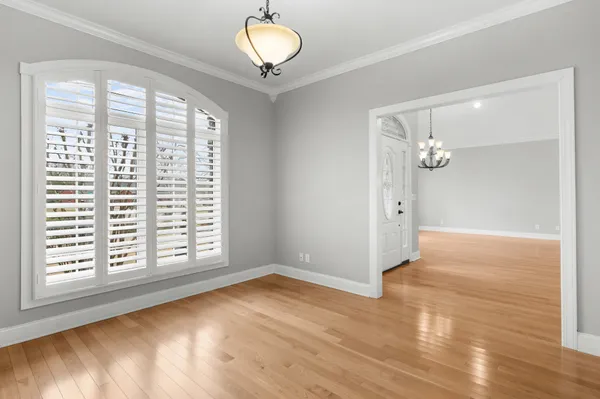 a view of an empty room with wooden floor and a ceiling fan