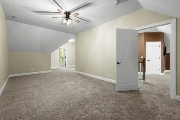 an empty room with windows and ceiling fan
