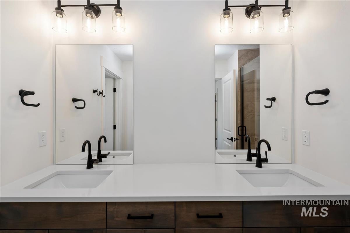 768 South Calhoun Lane Star, ID 83669 - Photo 24 of 36 Double vanity featuring integrated sinks, white countertops, dark wood-finish cabinetry, and matte black fixtures