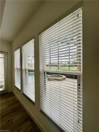 an empty room with wooden floor ceiling fan and window