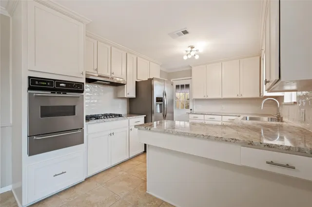 a kitchen with granite countertop white cabinets and stainless steel appliances