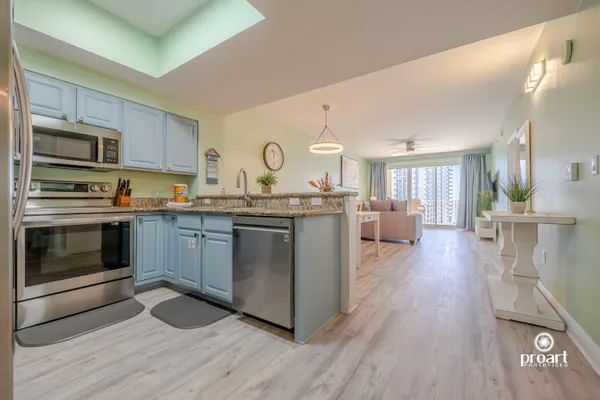 a kitchen with stainless steel appliances granite countertop a stove a sink dishwasher a microwave oven and a dining table with wooden floor