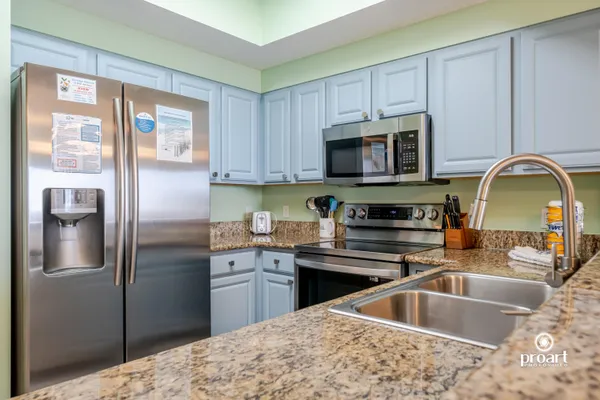 a kitchen with stainless steel appliances granite countertop a sink a stove and refrigerator