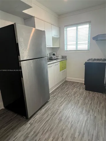 a kitchen with granite countertop a refrigerator and a stove top oven