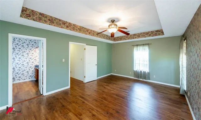 a view of a room with wooden floor chandelier fan and windows
