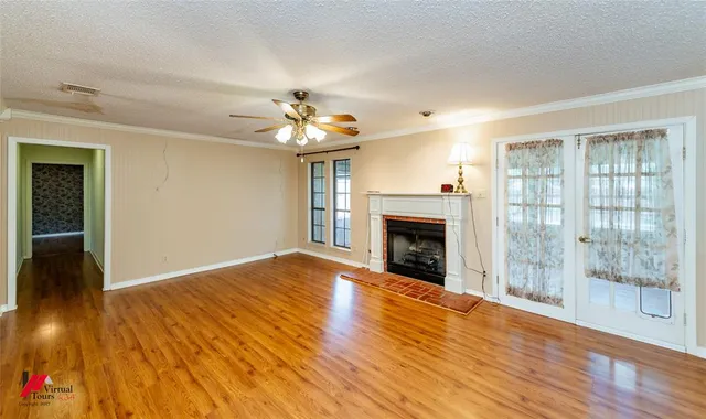 a view of an empty room with wooden floor and a fireplace