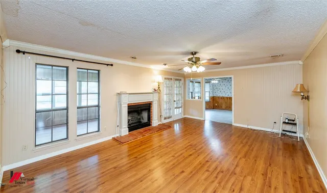 an empty room with wooden floor fireplace and windows