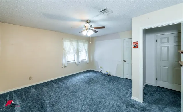 an empty room with fan and windows