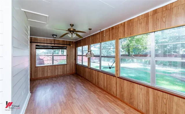 a view of empty room with wooden floor and fan