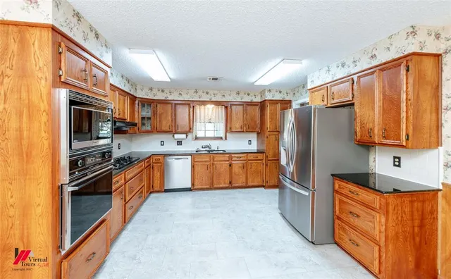 a large kitchen with stainless steel appliances granite countertop a stove a sink dishwasher and a refrigerator