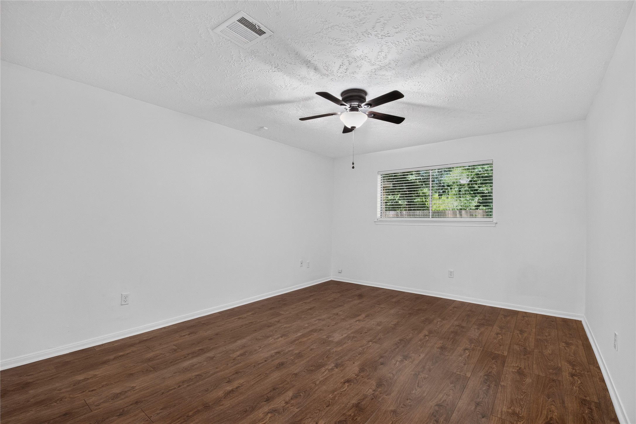 25223 Lynbriar Lane Spring, TX 77373 - Photo 13 of 32 The spacious primary bedroom offers plenty of room for large furniture and features a ceiling fan, beautiful wood-look flooring, and a peaceful backyard view.