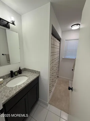 a bathroom with a granite countertop sink a mirror and a shower