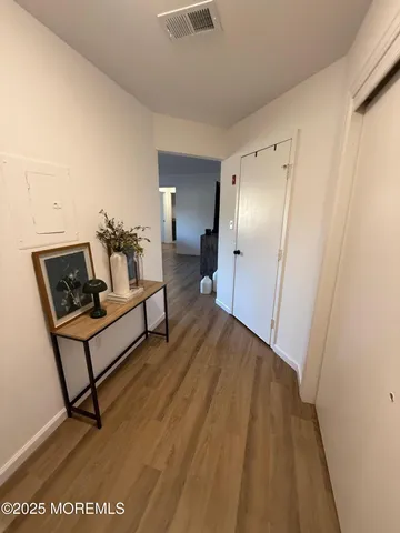 a view of a hallway with wooden floor and furniture