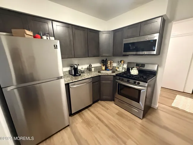 a white refrigerator freezer sitting inside of a kitchen with stainless steel appliances wooden floor