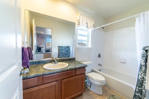a bathroom with a granite countertop sink toilet mirror and shower
