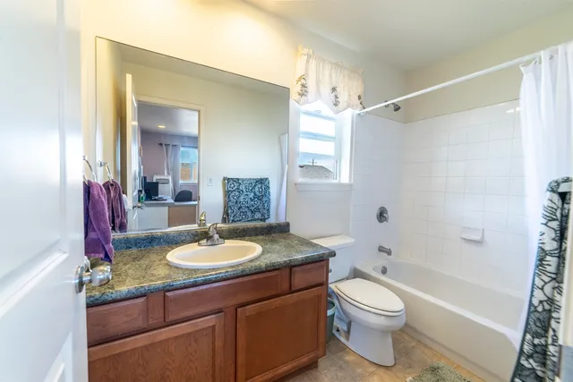 a bathroom with a granite countertop sink toilet mirror and shower