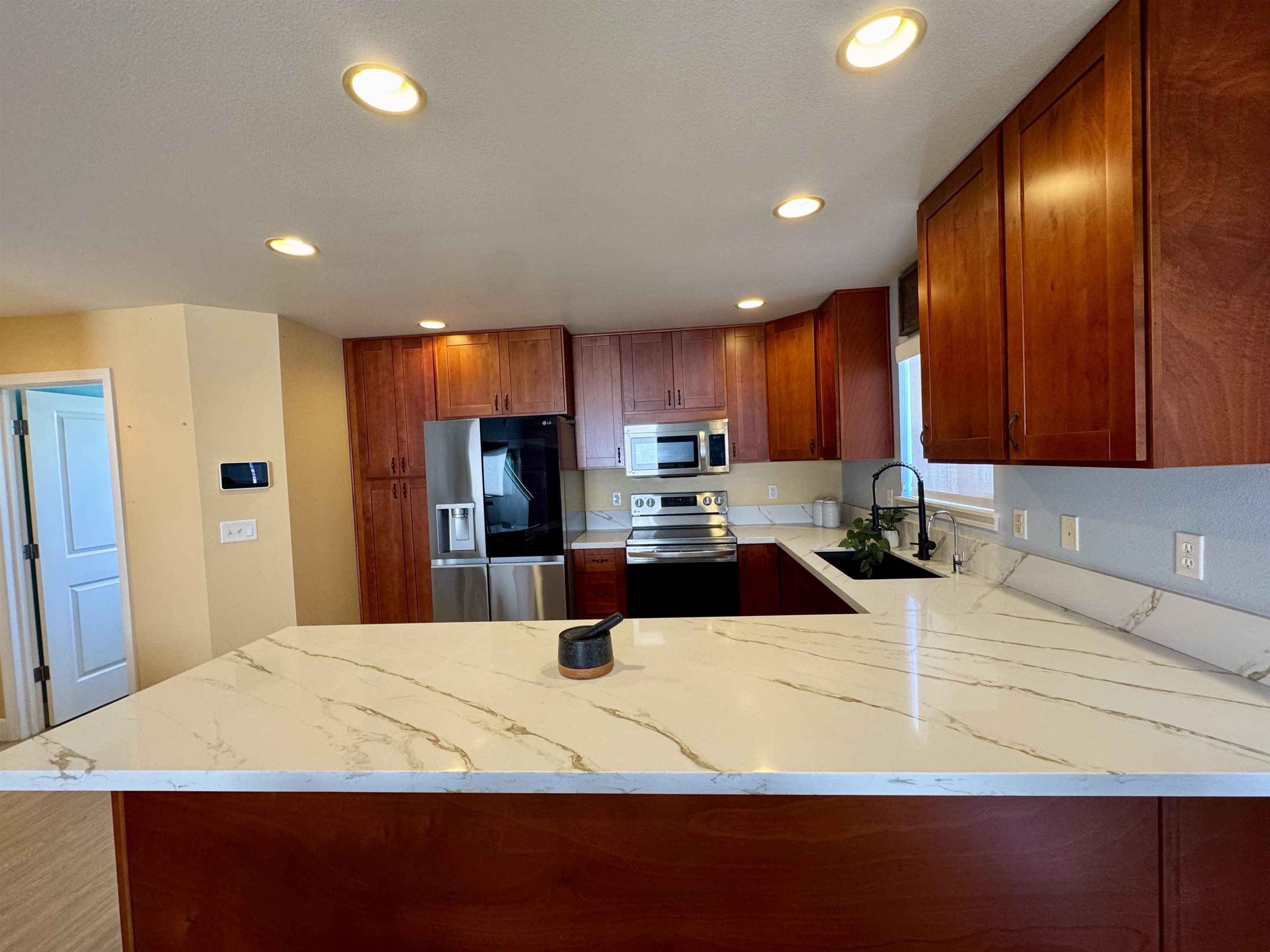 159 Iniiniki Street Wailuku, HI 96793 - Photo 3 of 33 a kitchen with kitchen island granite countertop wooden cabinets a refrigerator and a sink