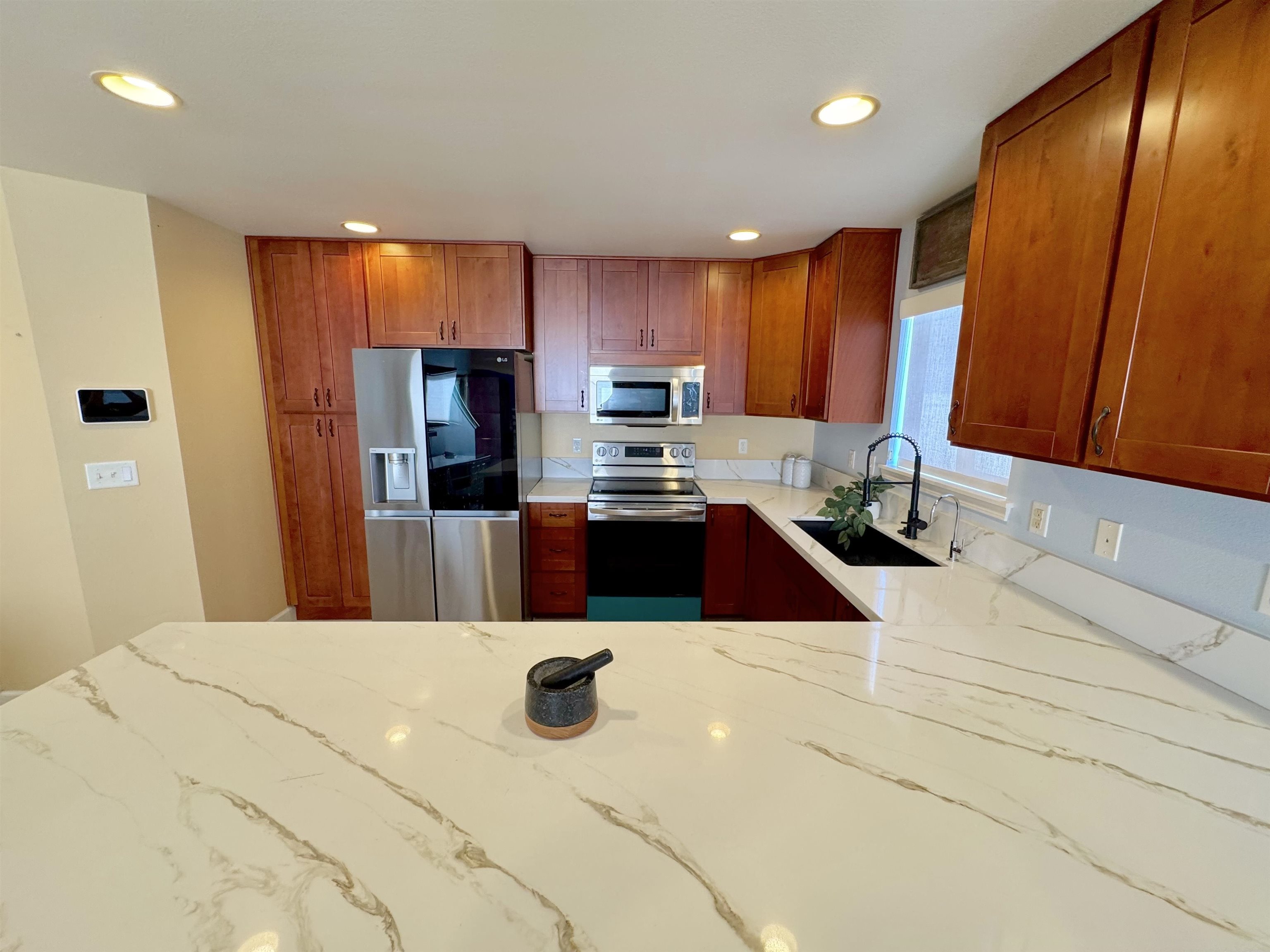 159 Iniiniki Street Wailuku, HI 96793 - Photo 4 of 33 a kitchen with stainless steel appliances a stove a refrigerator a sink a dining table and chairs with wooden floor