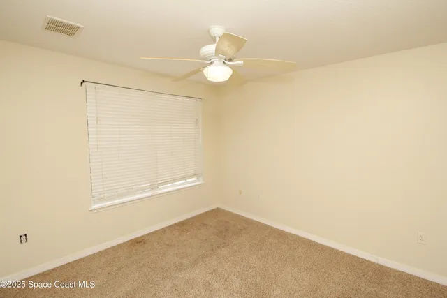 an empty room with a windows and ceiling fan