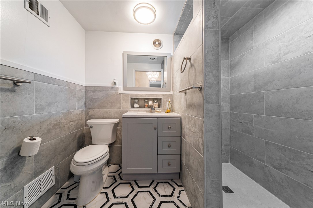 13800 Fairhill Road, Unit 306 Cleveland, OH 44120 - Photo 12 of 48 En-suite bath attached to the primary bedroom featuring a walk-in shower, vanity, classic wainscoting, and tiled walls.