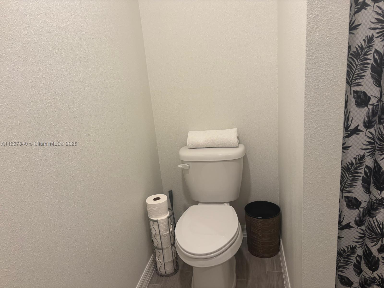 1073 Southwest Eureka Avenue, Unit 1073 Port St. Lucie, FL 34953 - Photo 14 of 25 a white toilet sitting next to a shower curtain