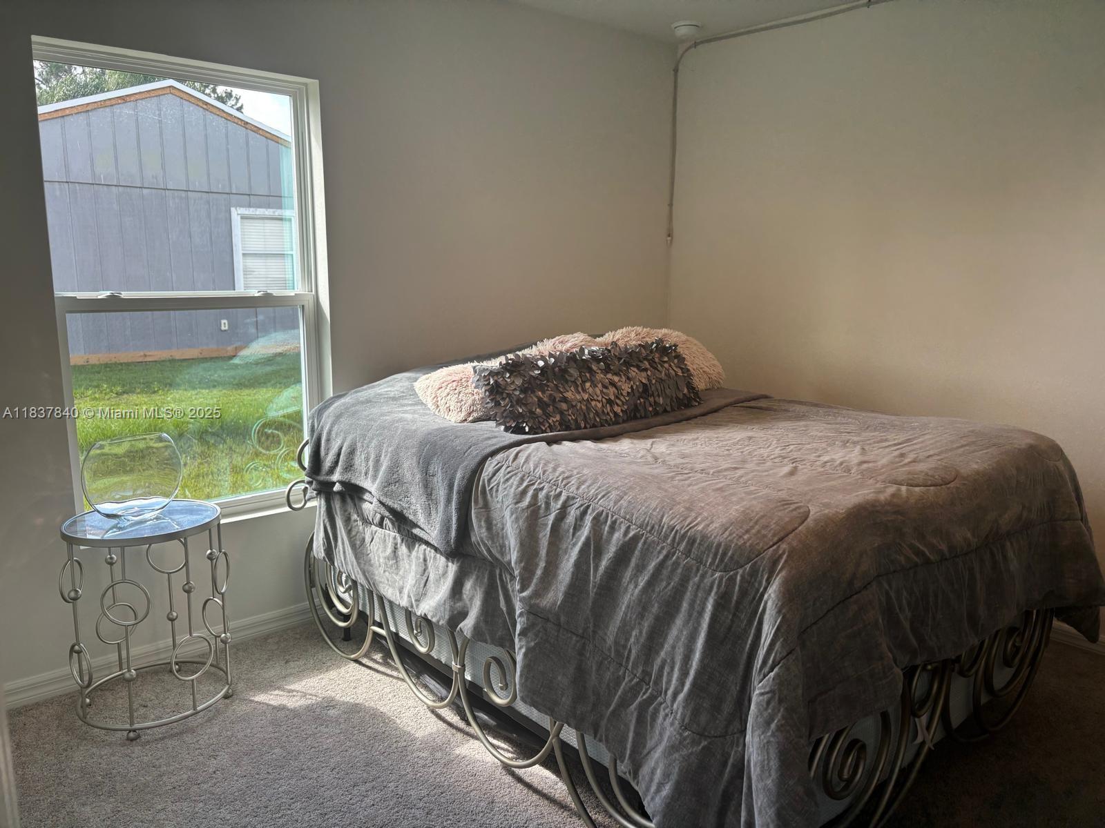 1073 Southwest Eureka Avenue, Unit 1073 Port St. Lucie, FL 34953 - Photo 17 of 25 a bedroom with a bed a mirror and a window