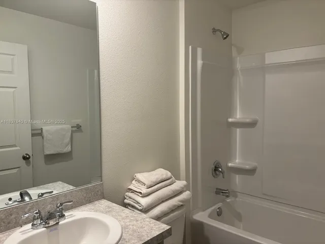 a bathroom with a granite countertop sink a toilet and shower