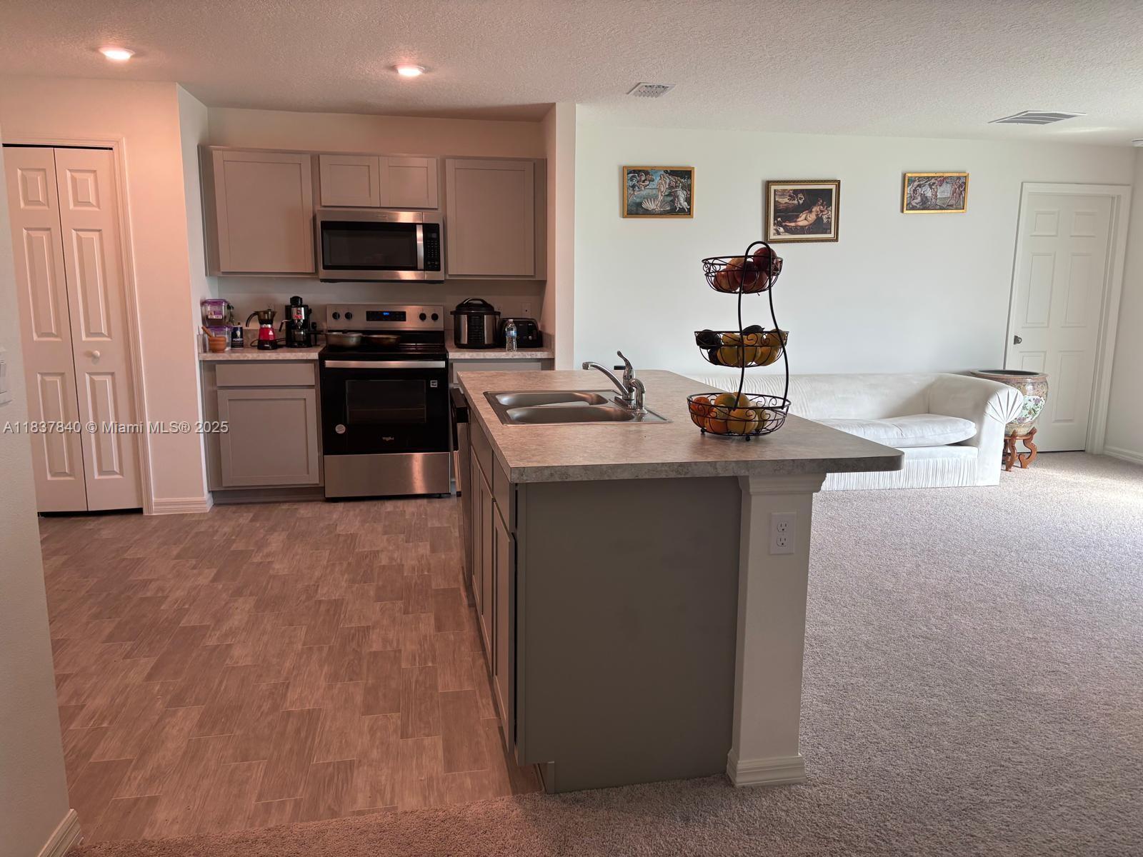1073 Southwest Eureka Avenue, Unit 1073 Port St. Lucie, FL 34953 - Photo 4 of 25 a kitchen with stainless steel appliances granite countertop a sink stove and refrigerator