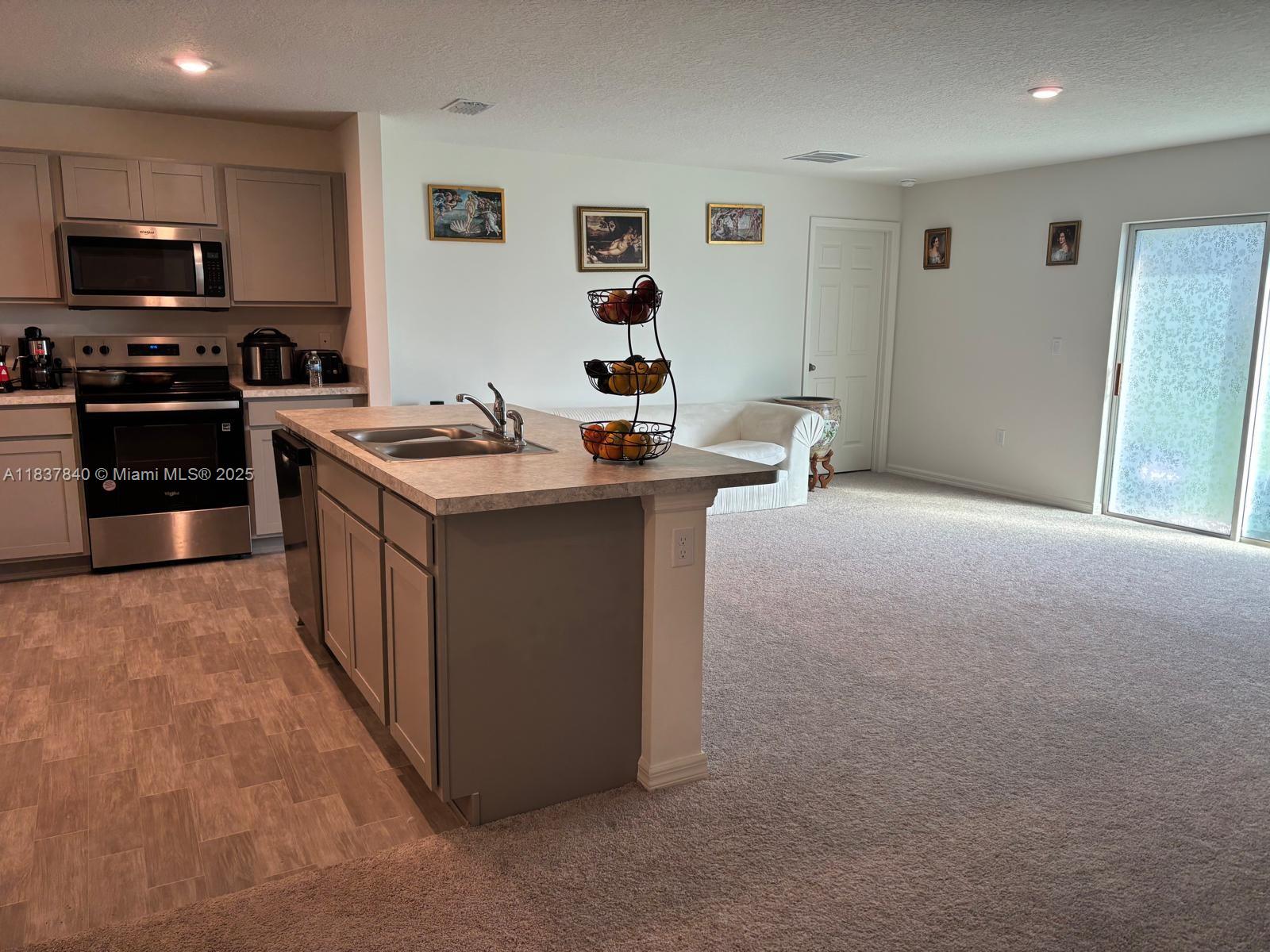 1073 Southwest Eureka Avenue, Unit 1073 Port St. Lucie, FL 34953 - Photo 6 of 25 a kitchen with stainless steel appliances granite countertop a stove top oven a sink dishwasher and a microwave oven on the blue kitchen countertops