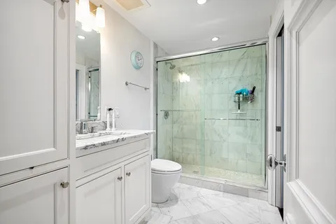 a bathroom with a shower sink vanity mirror and toilet