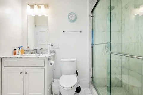 a bathroom with a toilet sink vanity and shower