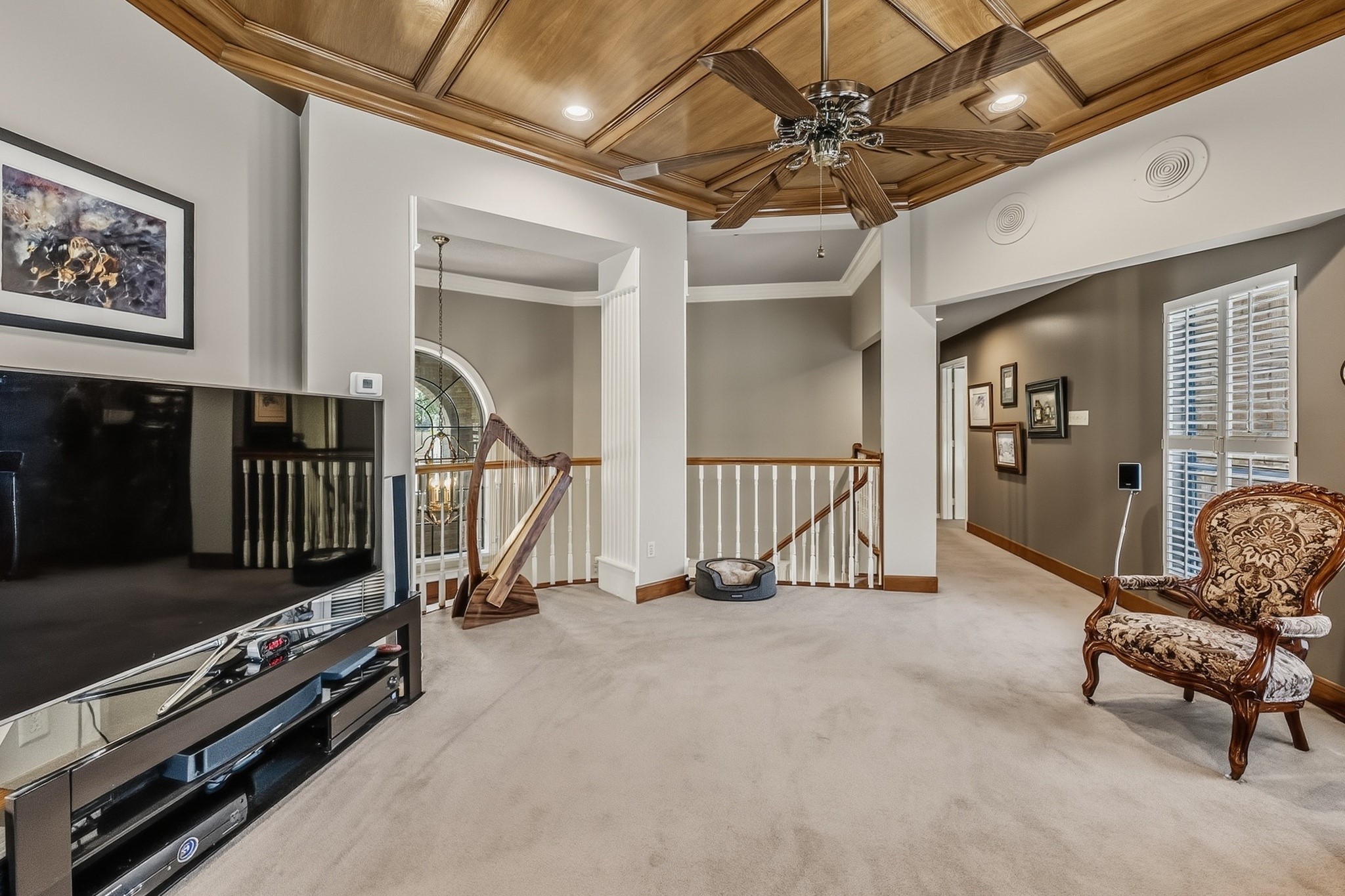 6047 Spring Creek Lane Spring, TX 77379 - Photo 23 of 50 Anchored by a richly detailed wood ceiling and generous proportions, the upstairs family room offers a comfortable setting for movie nights, game days, or quiet evenings at home. Thoughtfully placed windows and layered architectural detail give the space a warm, regal character without feeling overly formal.