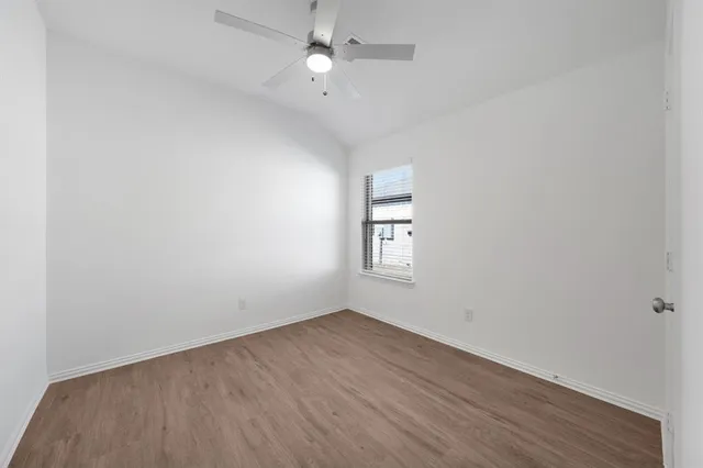 an empty room with wooden floor and ceiling fan