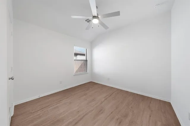 an empty room with a window and a fan