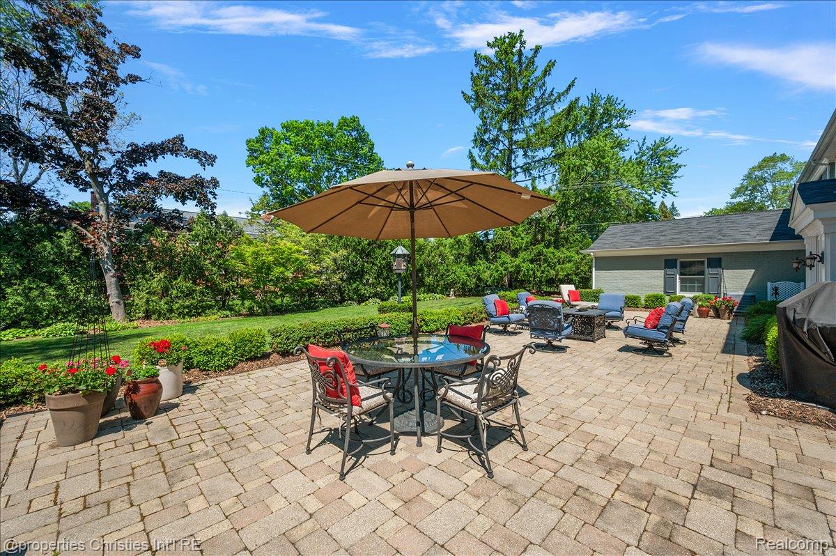 135 Clifton Road Bloomfield Hills, MI 48301 - Photo 72 of 77 Expansive paver patio featuring a dining area, a separate seating area, and a lush green lawn
