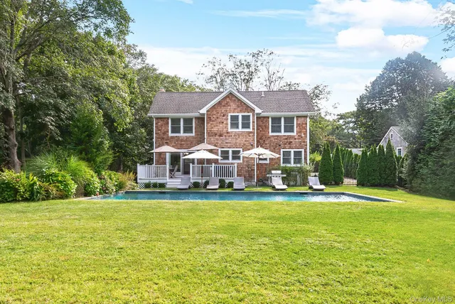 a view of a house with a big yard and large trees